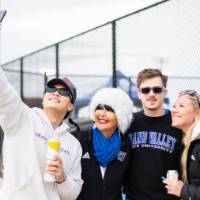 President Mantella smiles with three alumni while taking a selfie